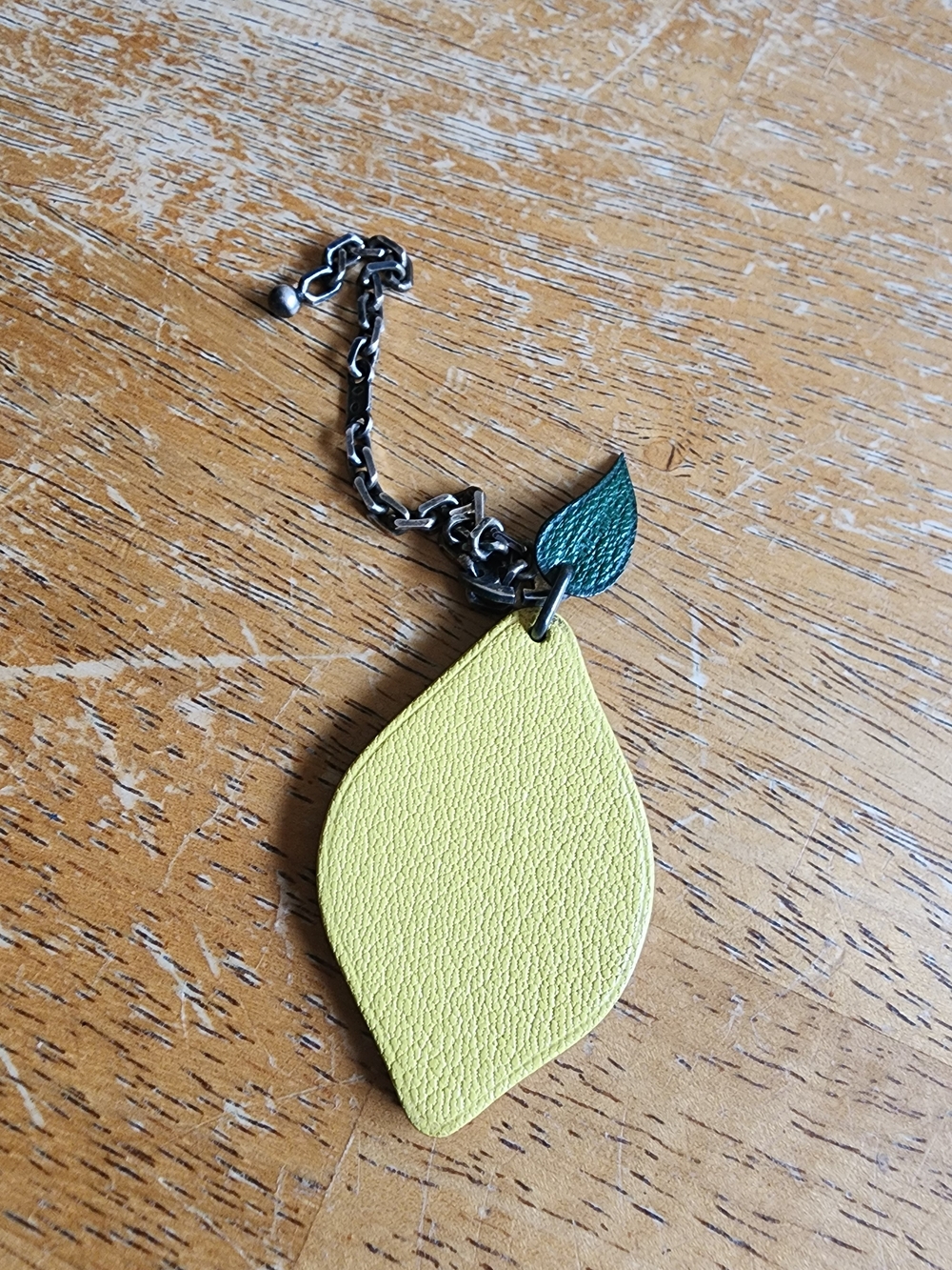 Hermès leather lemon bag charm featuring a green leaf.